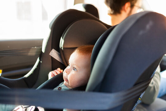 Baby Strapped Into Rear Facing Child Car Seat With Parent In Passenger Seat In Front