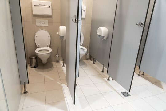 Pair of classic toilet cubicles with an open door in a public restroom