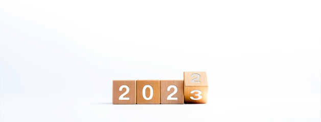 2023 happy new year concept banner. Flipping the 2022 to 2023 year numbers calendar on wooden cube...