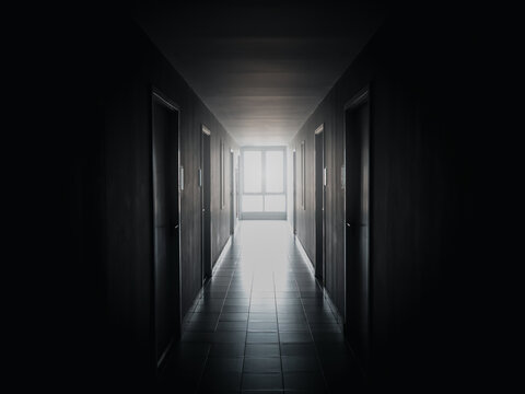 The light at the window at end of the way on dark mysterious corridor in building. Door room perspective in lonely quiet building with walkway, black and white style. hope, brave and fear concept.