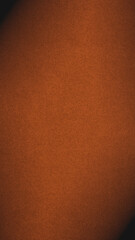 Dark orange colored paper texture. Bright brown vertical background. Mobile phone wallpaper with vignetting. Textured surface, fibers and irregularities are visible. Top-down