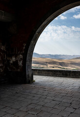 beautiful and endless landscape through the arch of a stone structure