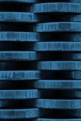 Stack of coins close up. Coin texture. Blue tinted vertical background made of many coin edges. Economy finance and bank wallpaper. Abstract money wall. Taxes, credit and currency exchange. Macro