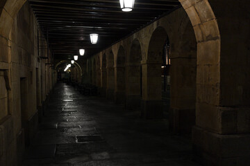 Fototapeta premium Stone arcades and iron lampposts hanging in the arcades of San Antonio outside the Plaza Mayor in Salamanca
