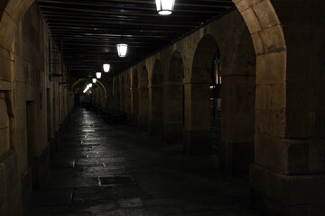 Stone arcades and iron lampposts hanging in the arcades of San Antonio outside the Plaza Mayor in Salamanca