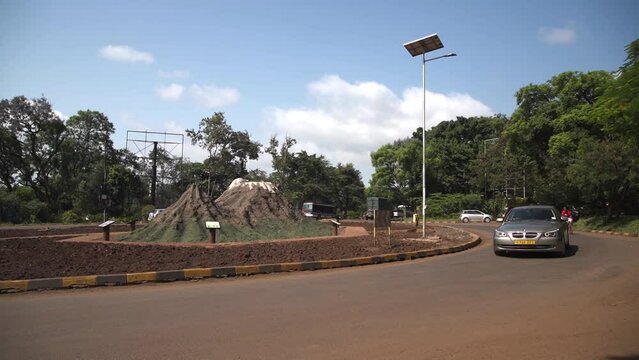 African roundabout road with huge termite mound termitary in the middle traffic.