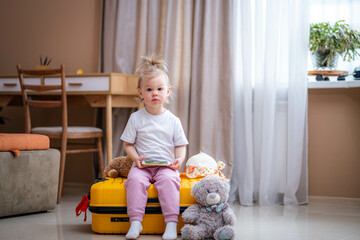 Little baby girl sitting on yellow suitcase baggage luggage, family ready to go for traveling on...