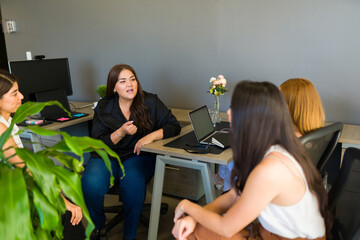 Diverse women listening to a female co-worker talk about business