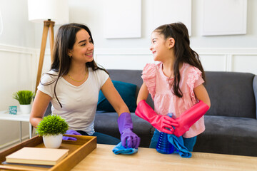 Hispanic mom and child smiling and doing house chores together