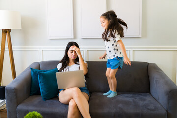 Tired mom parenting her daughter and telecommuting