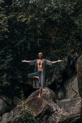 handsome bearded man posing on a mountain in the jungle, tourist traveler