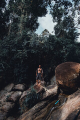 handsome bearded man posing on a mountain in the jungle, tourist traveler