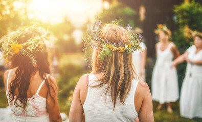 Women in flower wreath on sunny meadow, Floral crown, symbol of summer solstice. - obrazy, fototapety, plakaty