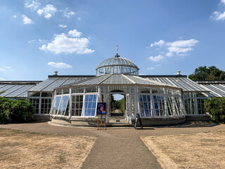 Fototapeta na wymiar Green house at Chiswick House and Gardens, London. Fragment of facade of Grade1 listed greenhouse housing historic camelia plants at Chiswick House and Gardens in West London. Sunny summer day