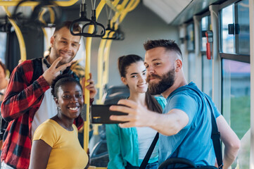 Multiracial group of friends taking selfie with a smartphone in a bus