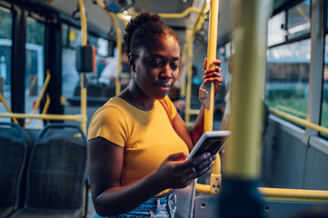 African american woman using smartphone while riding a bus in the night