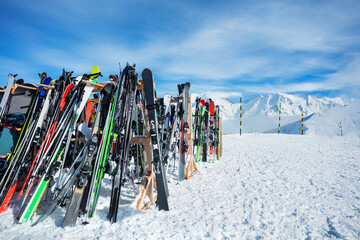 Many skis and snowboards stand on mountain top over summits