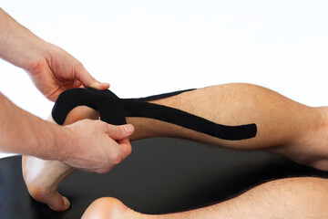 Kinesiology taping treatment with black tape on male patient injured Achilles tendon. Sports injury...