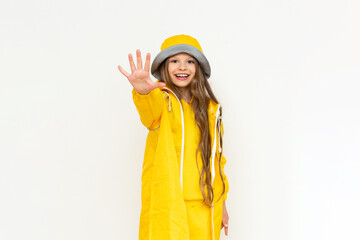 A child in a raincoat on a white isolated background. A little girl with long hair in a yellow raincoat and a panama hat.