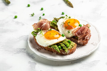 Grilled Toast witch Asparagus, fried egg, bacon jamon, ham, prosciutto on white background. Long banner format. top view