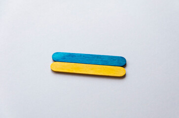 flag of ukraine from wooden sticks on a beige background in the center