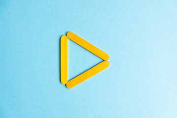 The play sign is yellow on a blue background. Inverted treulnik on a blue background. Geometric stick figure
