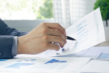 Close up of a Business man hand analyzing chart and graph showing changes on the market.