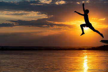 Kind springt mit einem langen Sprung in einen See