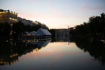 evening landscape on Chistoprudny Boulevard - Chistye Prudy, Moscow, Russia. Evening view of the city pond with ducks, a duck house and a cafe on the embankment