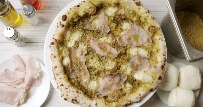 Pizza with Meat, Pesto, Cheese and Parmesan fresh out of the oven ready to eat. Delicious Italian pizza. Napoli Pizza. Food Service on white table and ingredient. Tasty Pizza with Cheese and Parmesan.