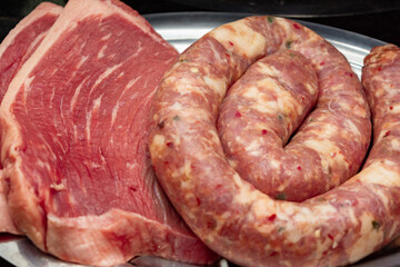 raw steaks and sausage, for barbecue