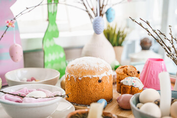 Table decoration for Easter celebration in kitchen.Tablescape for Easter holiday at home.Family religious traditional festive christianity,catholic meal food.Pop color eggs,cake,fun bunny,candy sweet