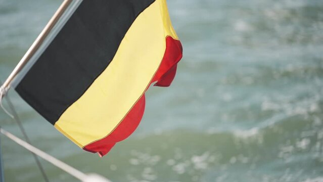 Flag of Belgium at the Nord sea at the aft of a sailing boat super slowmotion