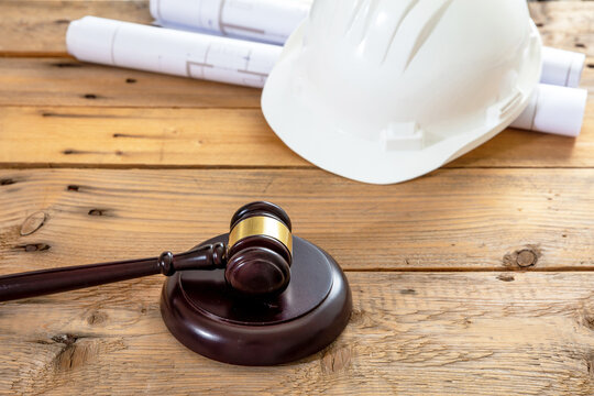 Construction, Labor law. Hardhat, judge gavel and building blueprint plans on table