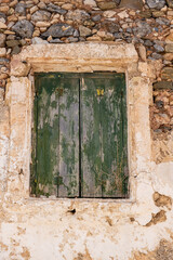 Fototapeta na wymiar Aged wooden closed shutters, peeled stone wall building facade, green window planks. Vertical