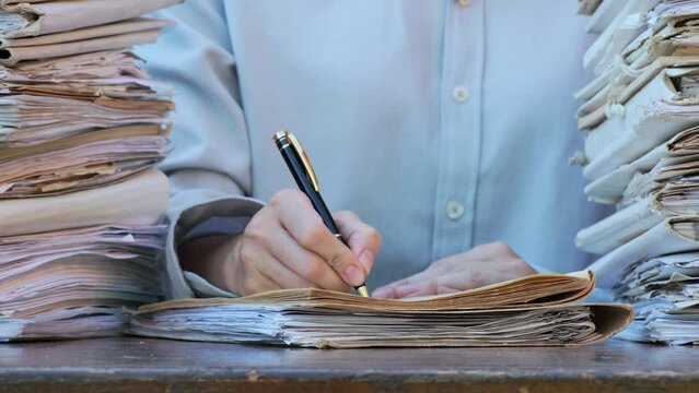 Business Concept. Young businesswoman putting signature on paper. Office worker in workplace signing documents contracts agreements. Female hands are working with paper Stacks of unfinished documents
