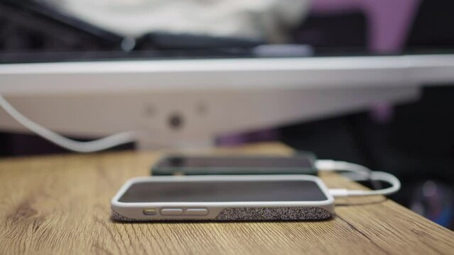 Hand of woman is plugging the power cord into a mobile phone covered with crystal or diamond case to charge. Tech mobile devices charging from power adapter.