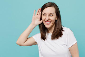 Young curious nosy caucasian woman 20s she wear white t-shirt try to hear you overhear listening intently isolated on plain pastel light blue cyan background studio portrait. People lifestyle concept.