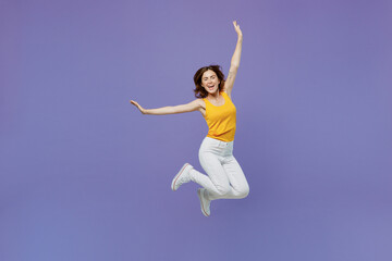 Fototapeta na wymiar Full body young overjoyed surprised excited happy fun woman 20s she wearing yellow tank shirt jump high with outstretched hands like fly in air isolated on plain pastel light purple background studio.