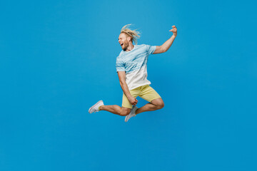 Fototapeta na wymiar Full body young blond man with dreadlocks 20s he wear white t-shirt jump high do playing guitar hand gesture isolated on plain pastel light blue background studio portrait. People lifestyle concept.