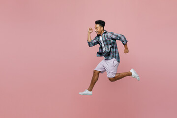 Fototapeta na wymiar Full body side view young hurrying caucasian man of African American ethnicity 20s he wear blue shirt run fast isolated on plain pastel light pink background studio portrait. People lifestyle concept.