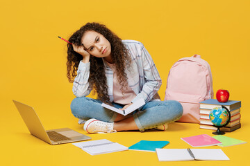 Full body sad tired young black teen girl student wear casual clothes backpack bag sit read book notebook prop up head isolated on plain yellow color background High school university college concept