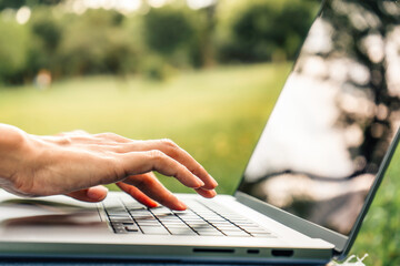 Close up of hands of woman using a laptop in a park