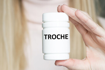 TROCHE word on the label of a white can in the hands of a doctor's girl, a medical concept