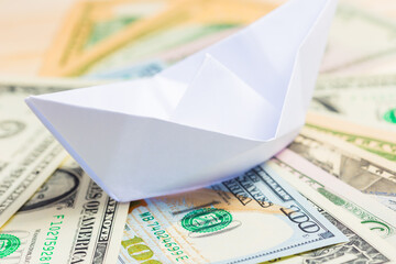 Dollars in banknotes and a paper ship in the style of origami