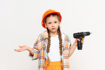 A child with a drill in his hands and wearing a protective construction helmet.The little girl wondered how to make repairs in the children's room. The concept of repair.