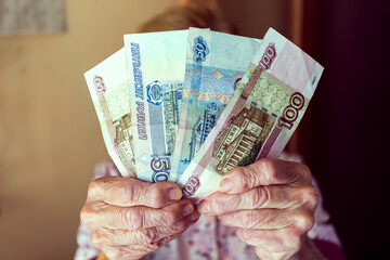 The hand of an elderly woman with money. Rubles from pensioner.