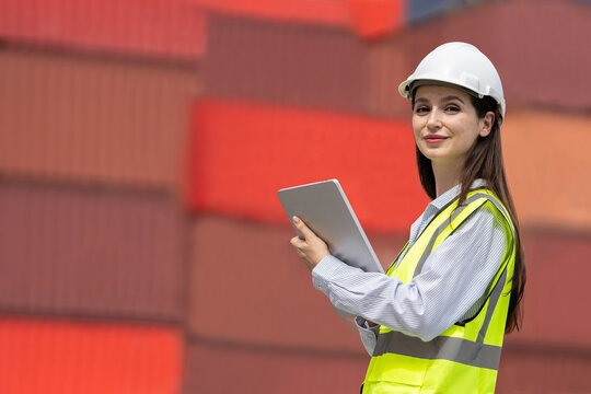 Portrait Caucasian woman worker working in container port terminal. Attractive female engineer people process orders and product at warehouse logistic in cargo freight ship for import export in harbor