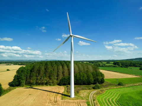 Mid level aspect aerial view of a wind turbine in a small rural wind farm in the English countryside