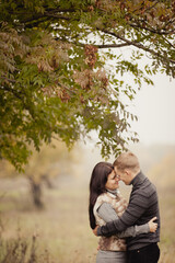 Fototapeta premium couple on autumn walk outdoors. Two lovers in autumn park. Love and tender touch. Foggy cloudy day filled with the warmth of love. Beautiful autumn landscape for couple